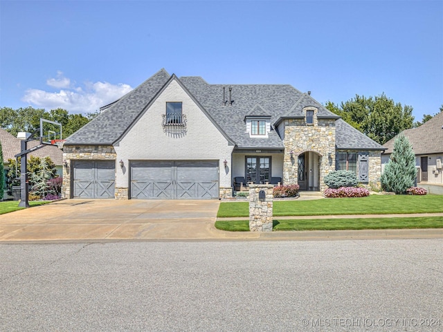 french country home featuring french doors, a garage, and a front yard