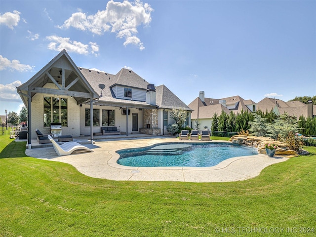 view of swimming pool with a jacuzzi, a patio area, outdoor lounge area, and a lawn