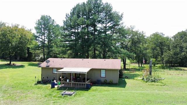 rear view of house featuring cooling unit and a lawn