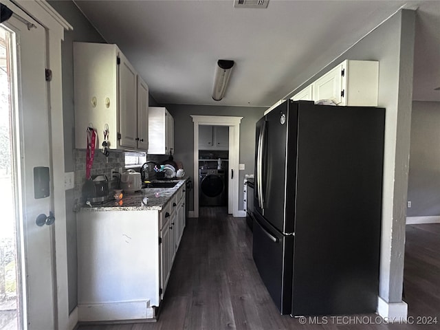 kitchen featuring white cabinets, black refrigerator, washer / clothes dryer, dark wood-type flooring, and tasteful backsplash