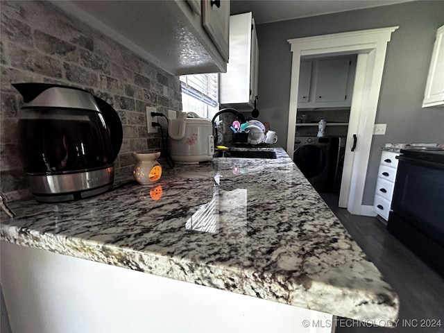 kitchen featuring black stove, white cabinetry, dark hardwood / wood-style flooring, sink, and washer / dryer