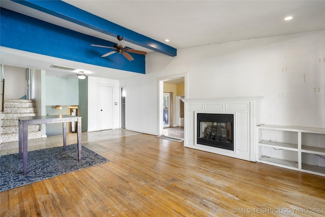 unfurnished living room with beam ceiling, a fireplace, visible vents, ceiling fan, and hardwood / wood-style floors