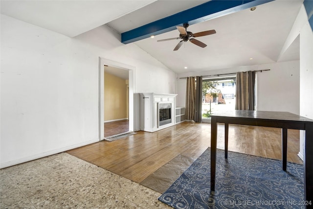 interior space featuring vaulted ceiling with beams, ceiling fan, a fireplace, wood finished floors, and baseboards