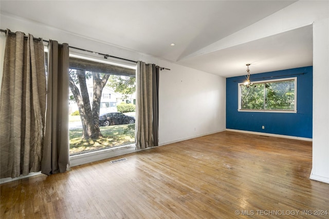 spare room featuring baseboards, visible vents, vaulted ceiling, and hardwood / wood-style floors