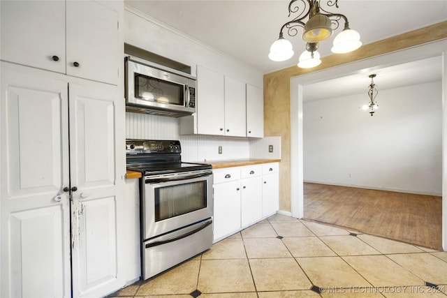 kitchen featuring light tile patterned floors, a chandelier, white cabinetry, appliances with stainless steel finishes, and decorative backsplash