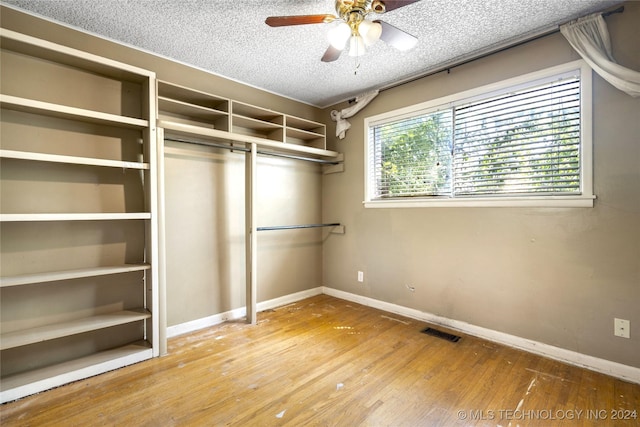 spacious closet with a ceiling fan, visible vents, and hardwood / wood-style floors