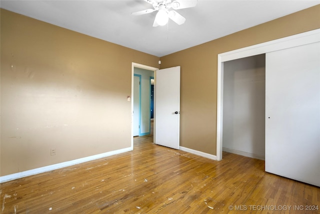 unfurnished bedroom featuring ceiling fan, a closet, hardwood / wood-style flooring, and baseboards