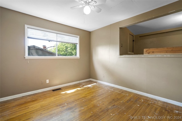 empty room featuring hardwood / wood-style flooring, visible vents, baseboards, and a ceiling fan