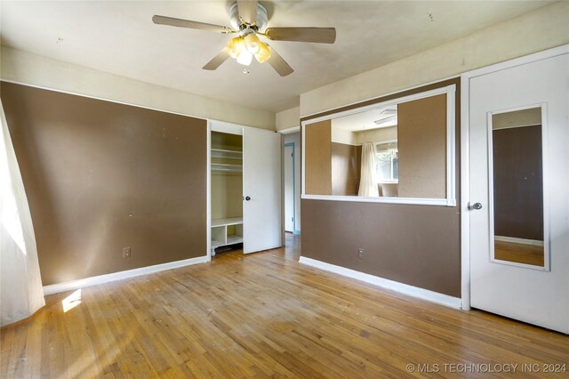 unfurnished room with a ceiling fan, wood-type flooring, and baseboards