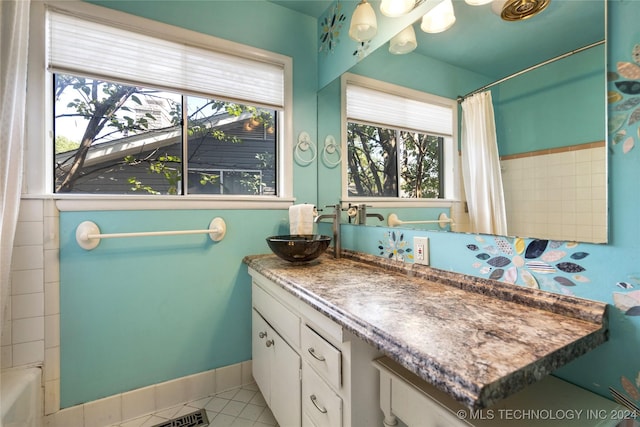 full bathroom with baseboards, a shower with shower curtain, tile patterned flooring, a washtub, and vanity