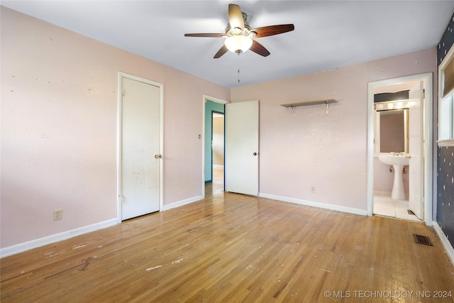 unfurnished bedroom featuring visible vents, ensuite bath, baseboards, and hardwood / wood-style flooring