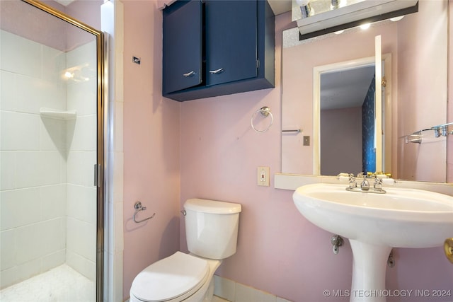 bathroom with toilet, a shower stall, and a sink