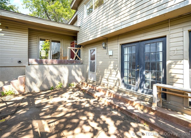 property entrance featuring a shingled roof, mansard roof, and french doors