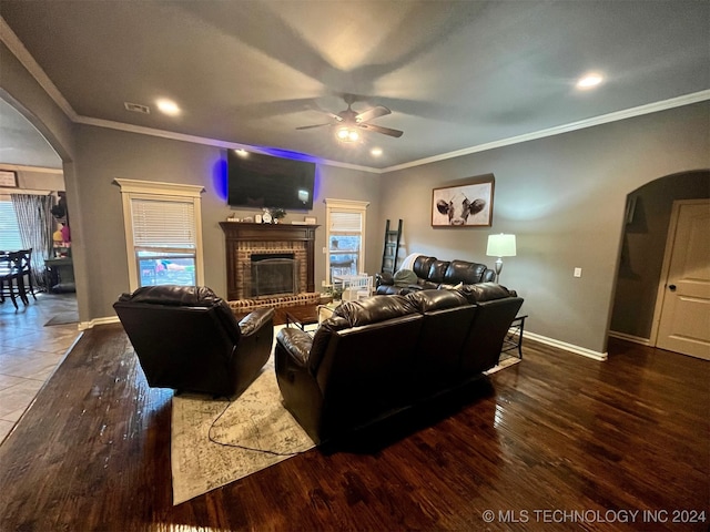 living room featuring crown molding, dark wood-type flooring, a fireplace, and ceiling fan