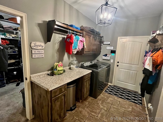 laundry room with dark carpet, washer and clothes dryer, a notable chandelier, and cabinets