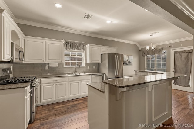 kitchen with a breakfast bar, stainless steel appliances, sink, white cabinets, and a center island