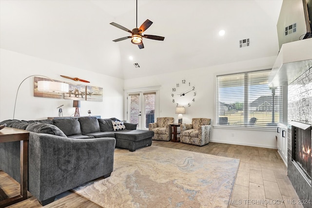 living room featuring light hardwood / wood-style floors, a wealth of natural light, high vaulted ceiling, and french doors