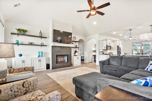 living room with ceiling fan, sink, light hardwood / wood-style flooring, and high vaulted ceiling