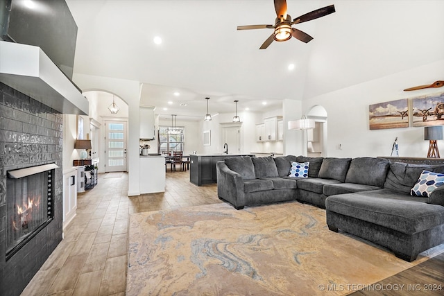 living room featuring ceiling fan, a tile fireplace, and lofted ceiling