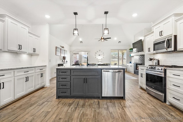 kitchen featuring appliances with stainless steel finishes, lofted ceiling, white cabinetry, and pendant lighting