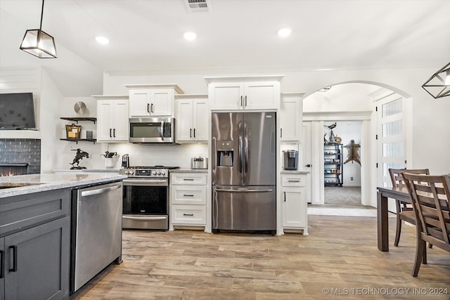 kitchen featuring white cabinetry, light hardwood / wood-style floors, stainless steel appliances, decorative backsplash, and decorative light fixtures