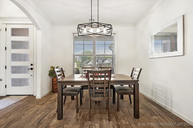 dining room with dark wood-type flooring, ornamental molding, and a chandelier