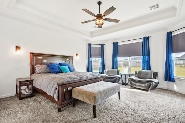 carpeted bedroom featuring ceiling fan and a tray ceiling