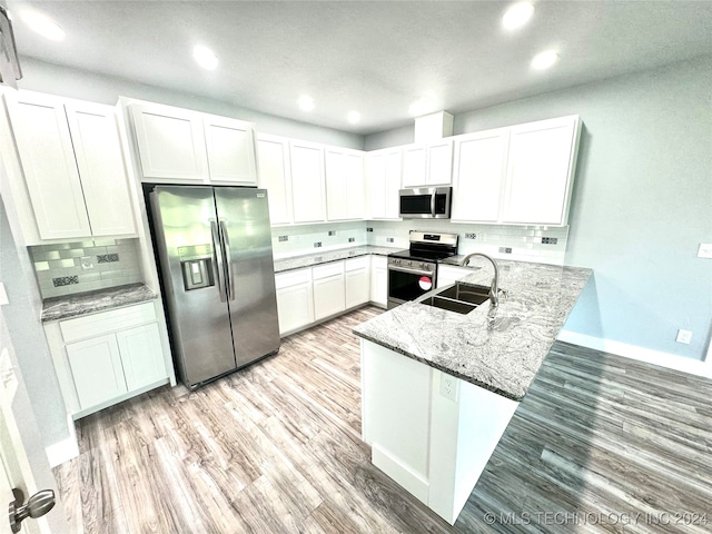 kitchen with stone countertops, light hardwood / wood-style flooring, appliances with stainless steel finishes, and white cabinets