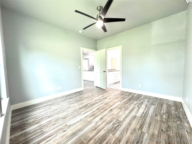 unfurnished bedroom with hardwood / wood-style floors, ceiling fan, and connected bathroom