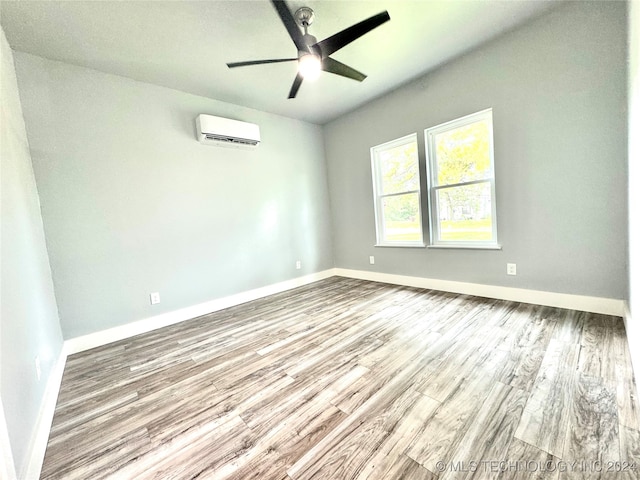 empty room featuring a wall mounted AC, ceiling fan, and hardwood / wood-style floors