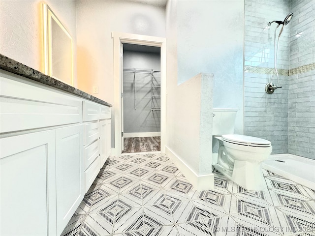 bathroom with vanity, toilet, tile patterned floors, and a tile shower