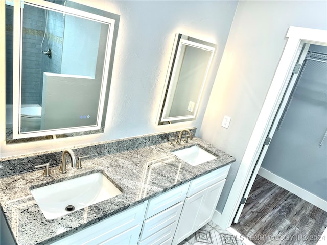 bathroom with vanity, toilet, a tile shower, and hardwood / wood-style floors