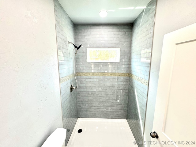 bathroom featuring toilet and a tile shower