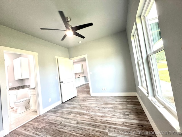 unfurnished bedroom with lofted ceiling, wood-type flooring, connected bathroom, and ceiling fan