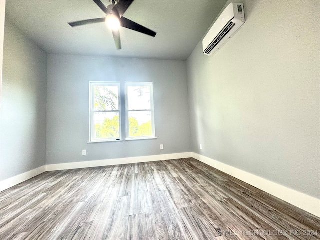 spare room featuring wood-type flooring, a wall unit AC, and ceiling fan