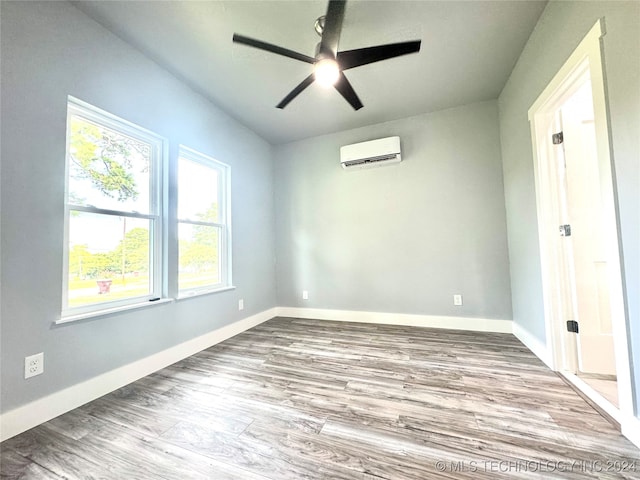 spare room with hardwood / wood-style flooring, a wall unit AC, and ceiling fan