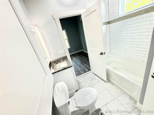 full bathroom with tiled shower / bath combo, vanity, toilet, and hardwood / wood-style floors