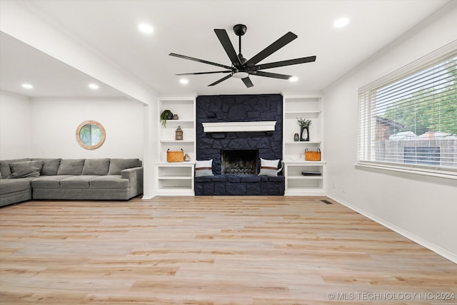 living room with ceiling fan, a stone fireplace, built in features, and light hardwood / wood-style floors