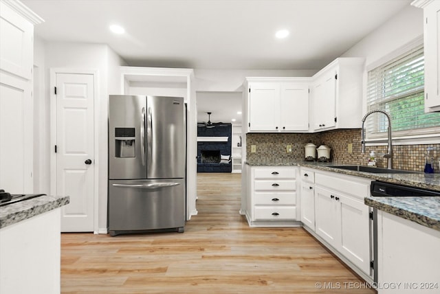 kitchen with dark stone countertops, white cabinetry, light hardwood / wood-style floors, and stainless steel fridge with ice dispenser