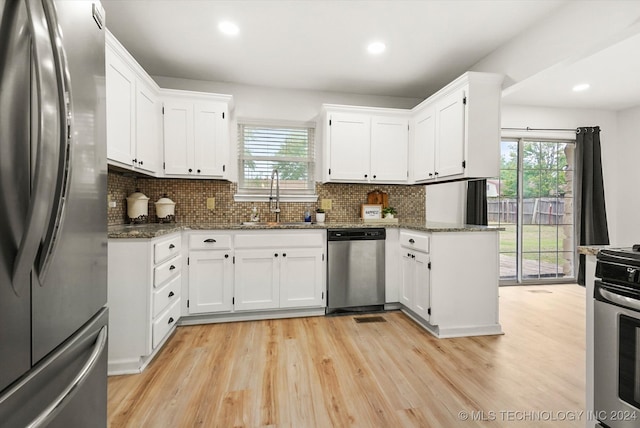 kitchen featuring appliances with stainless steel finishes, dark stone counters, sink, and white cabinets