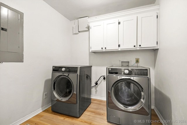 washroom featuring separate washer and dryer, light hardwood / wood-style floors, electric panel, and cabinets