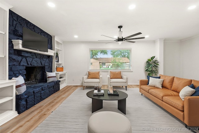 living room with ceiling fan, light hardwood / wood-style flooring, a fireplace, and crown molding