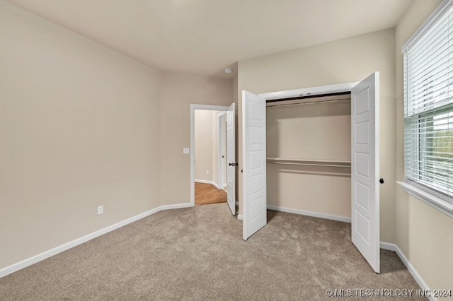 unfurnished bedroom featuring light carpet and a closet