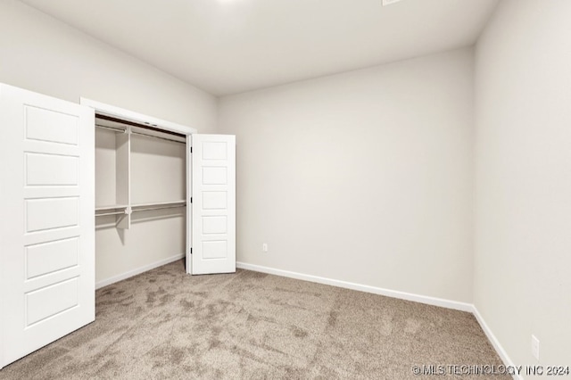 unfurnished bedroom with light colored carpet and a closet