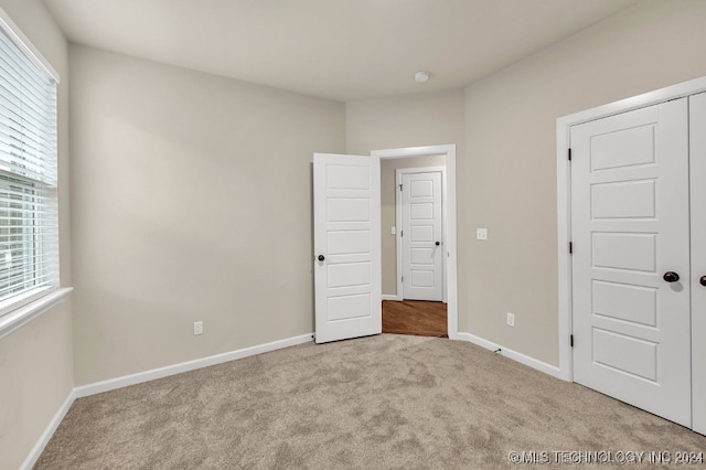 unfurnished bedroom featuring light colored carpet and a closet