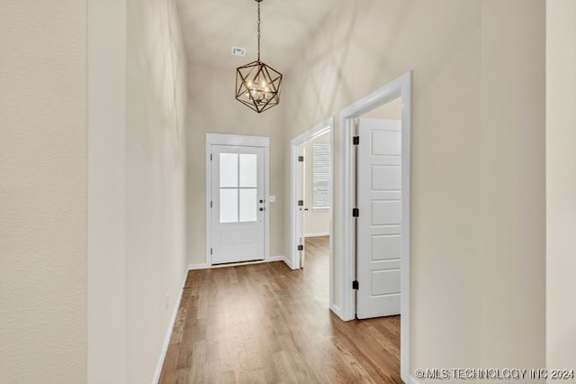 doorway to outside featuring a high ceiling, light hardwood / wood-style floors, and a chandelier