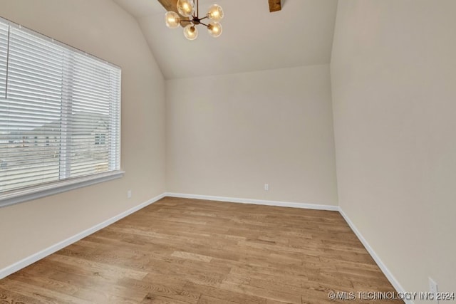 empty room featuring lofted ceiling, an inviting chandelier, and light hardwood / wood-style floors