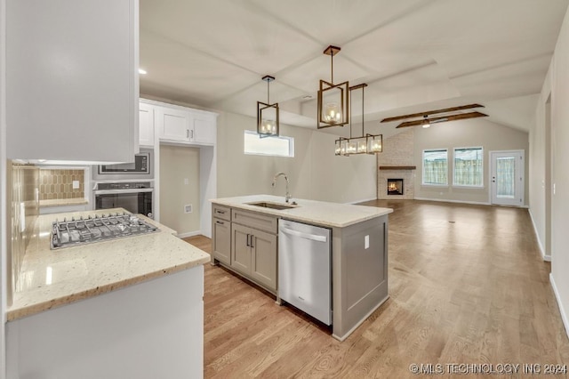 kitchen featuring white cabinets, a large fireplace, appliances with stainless steel finishes, sink, and ceiling fan