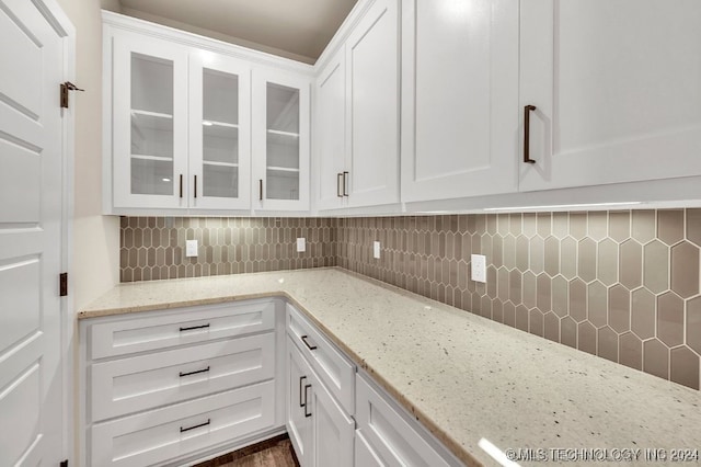 kitchen featuring dark hardwood / wood-style floors, light stone countertops, backsplash, and white cabinets