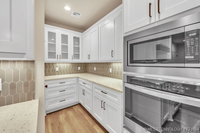 kitchen featuring white cabinets, light stone counters, stainless steel appliances, and light hardwood / wood-style floors